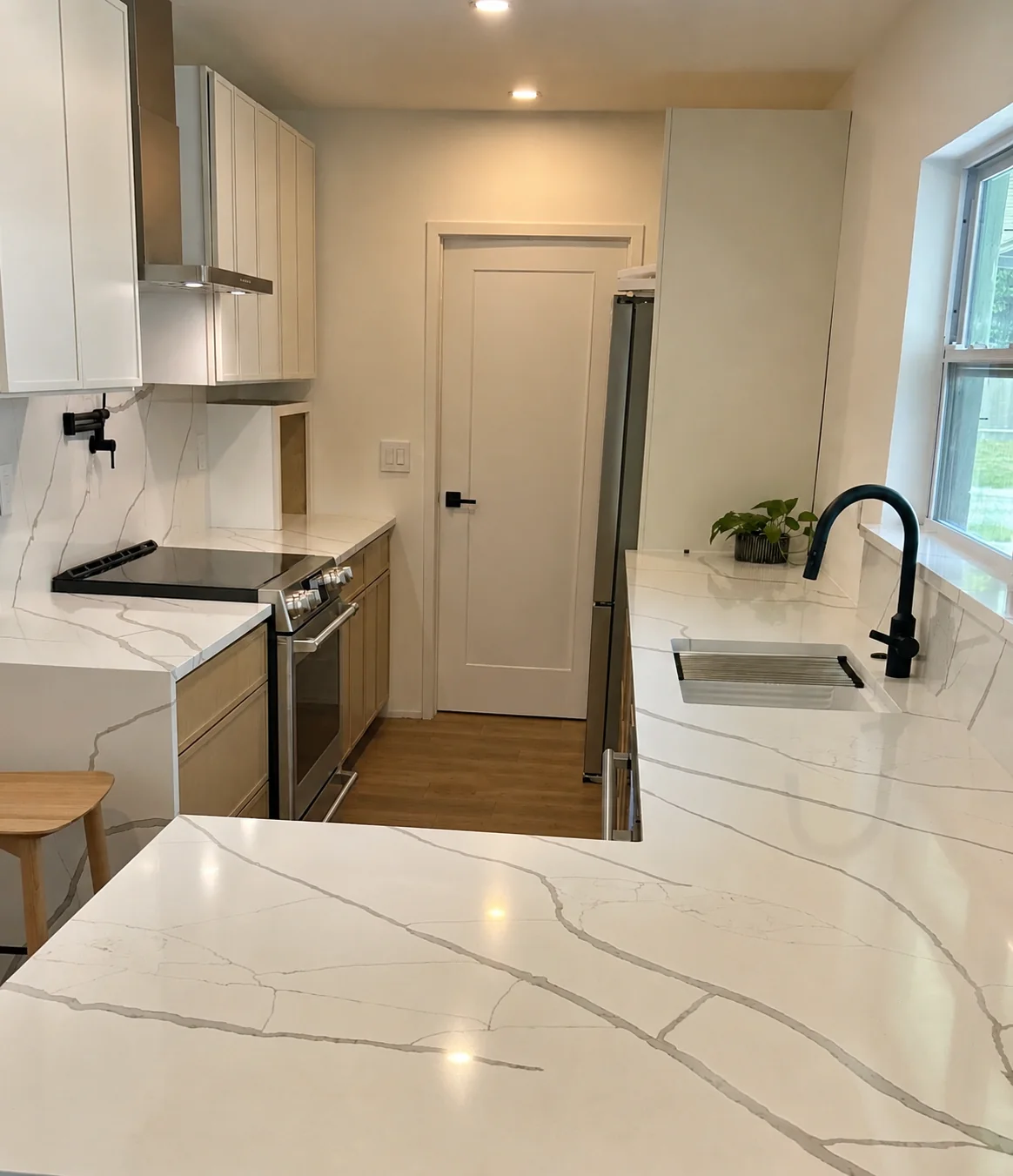 Refined galley kitchen with quartz counters, warm wood cabinetry, and off-white door