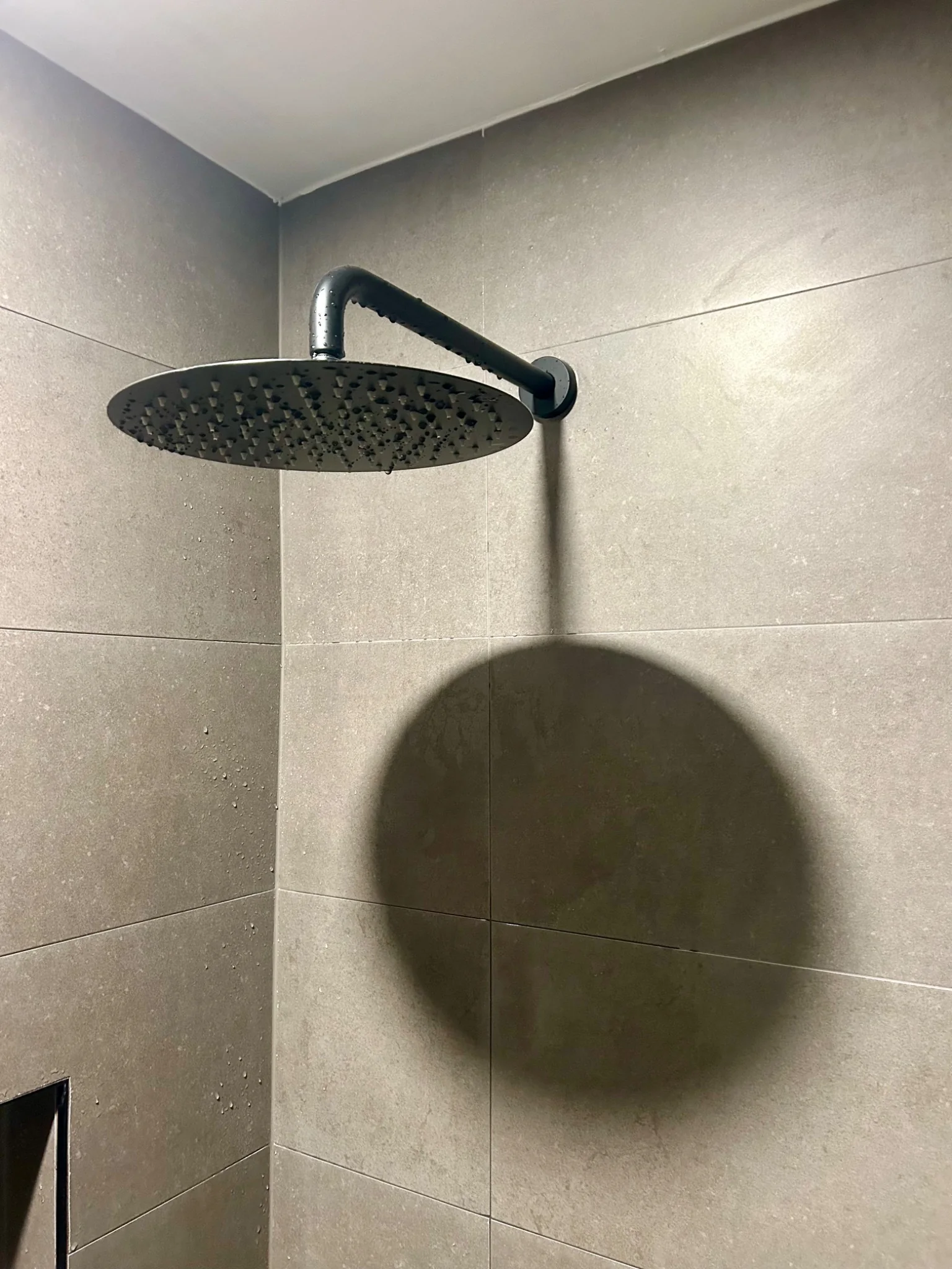 Shower head shadow on stone tile